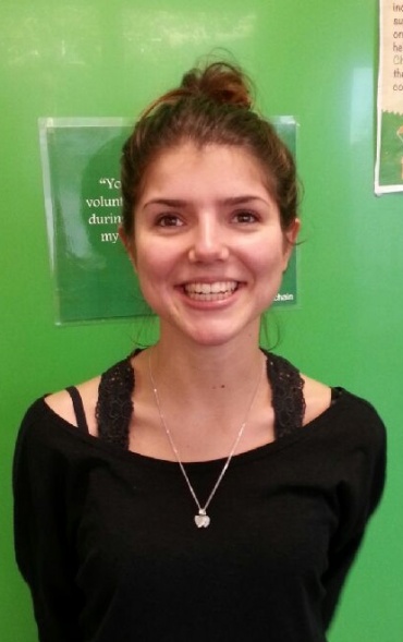 Giulia, standing in front of a green background smiling